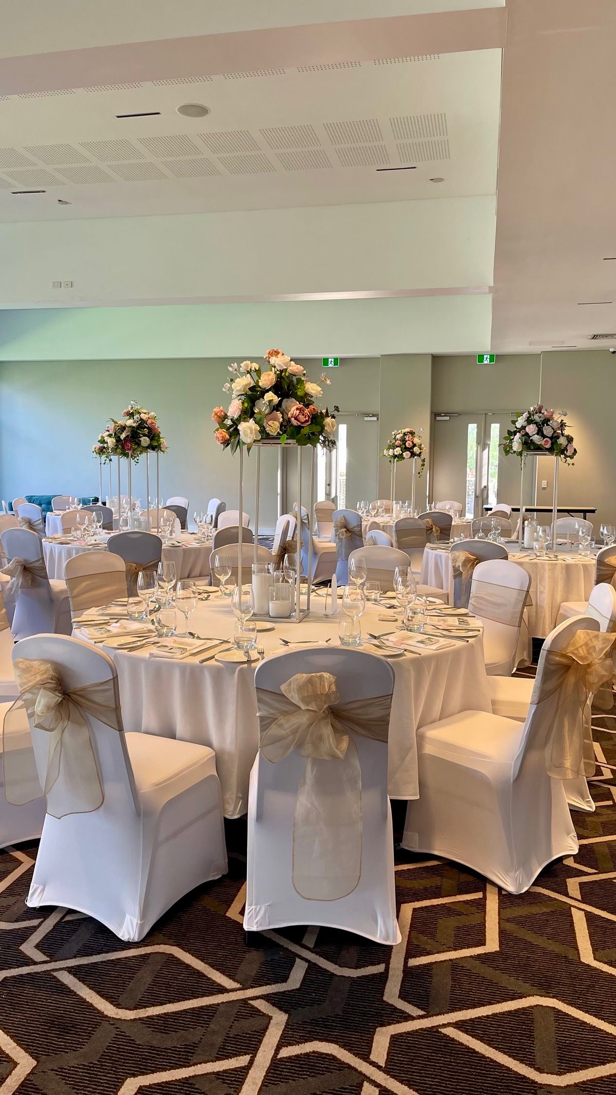 Elegant ballroom reception with tall floral centerpieces and draped chair sashes