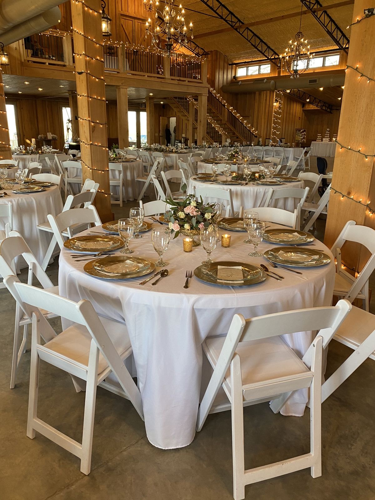 Rustic barn venue reception with string lights and gold place settings